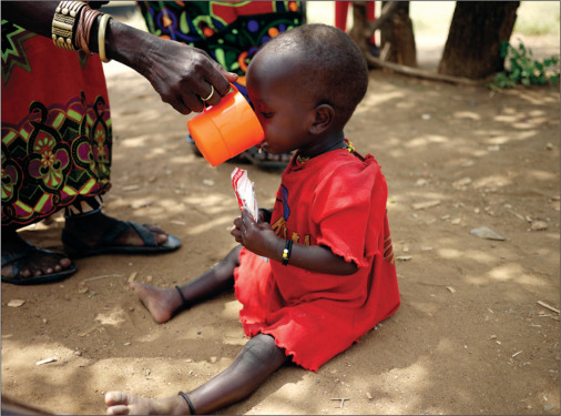 A young child in red receives food at a feeding station in Turkana, Kenya